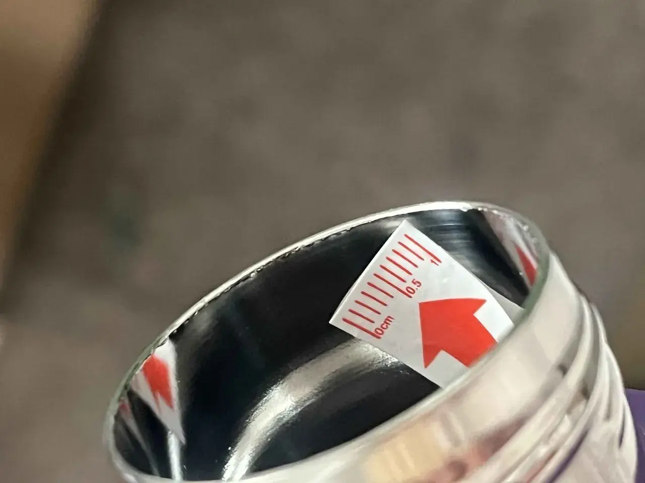 Close-up of a metal container rim with a red arrow marking the area to inspect.