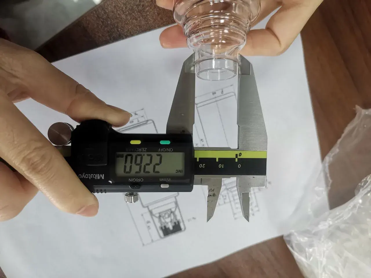 A product dimension measured with a digital caliper against a technical drawing during inspection.
