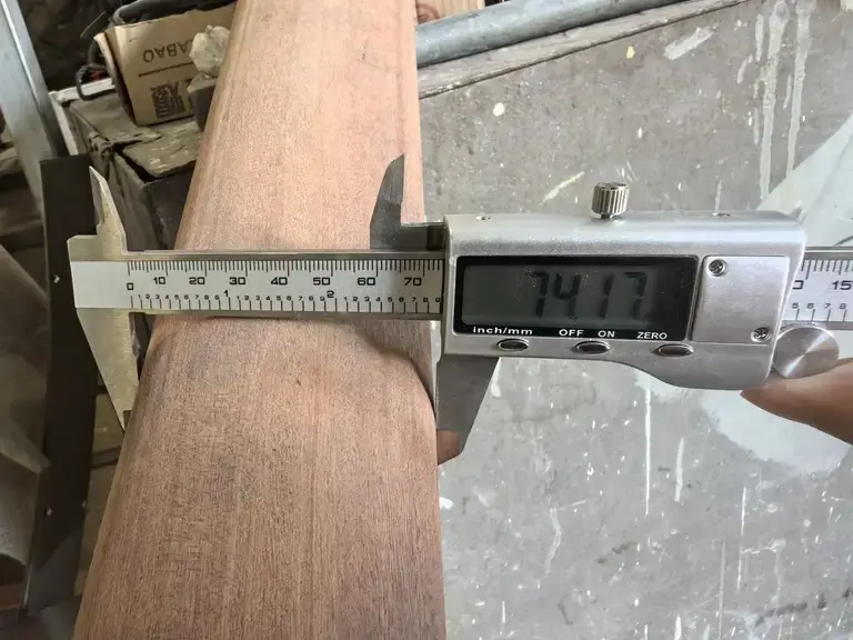 A wooden part measured with calipers during an inspection.