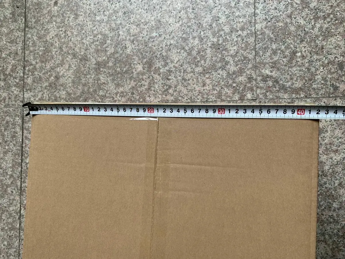 Dimension d'un carton contrôlée au mètre par rapport aux spécifications d'emballage.